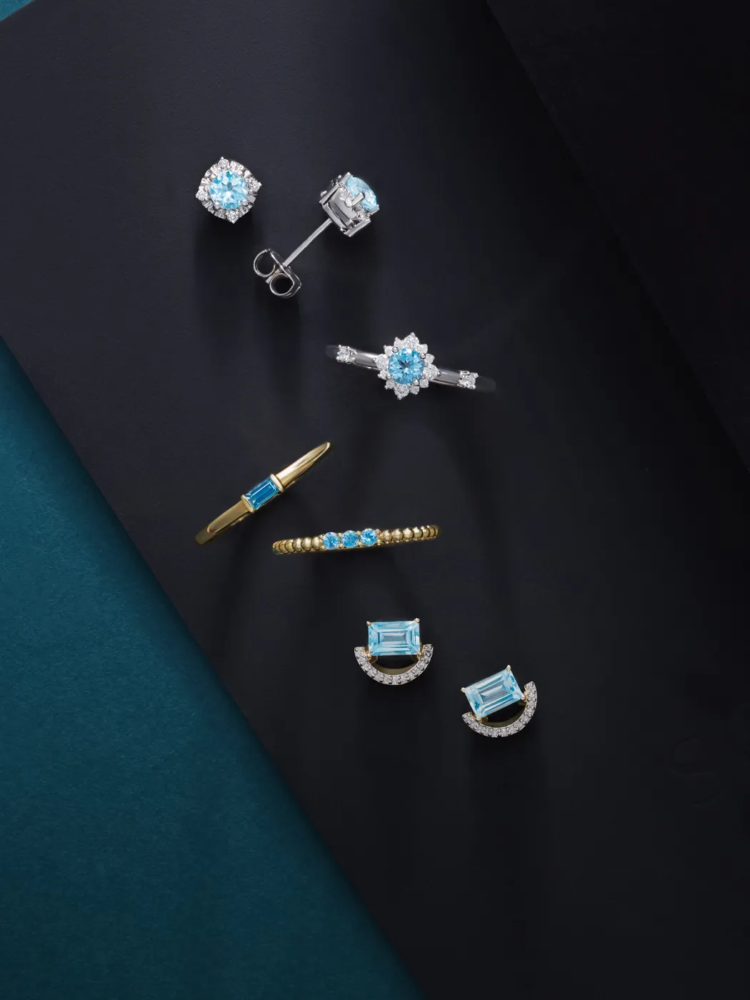 Aquamarine jewelry set on black background, featuring earrings, rings, and a bracelet.