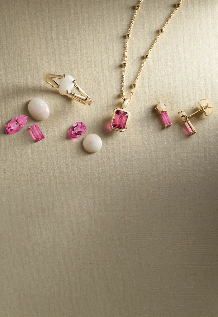 Jewelry set with pink and white gemstones on a textured surface.