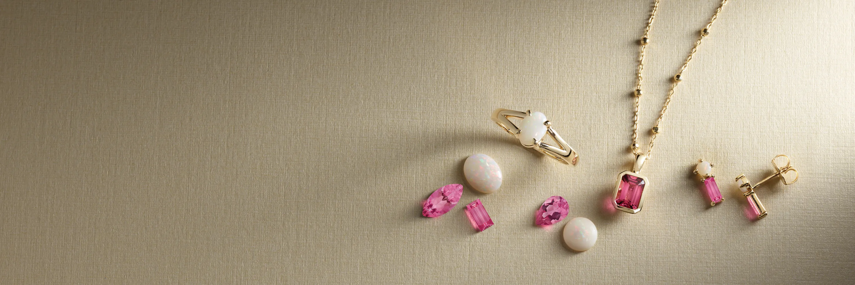 Jewelry set with pink and white gemstones on a textured surface.