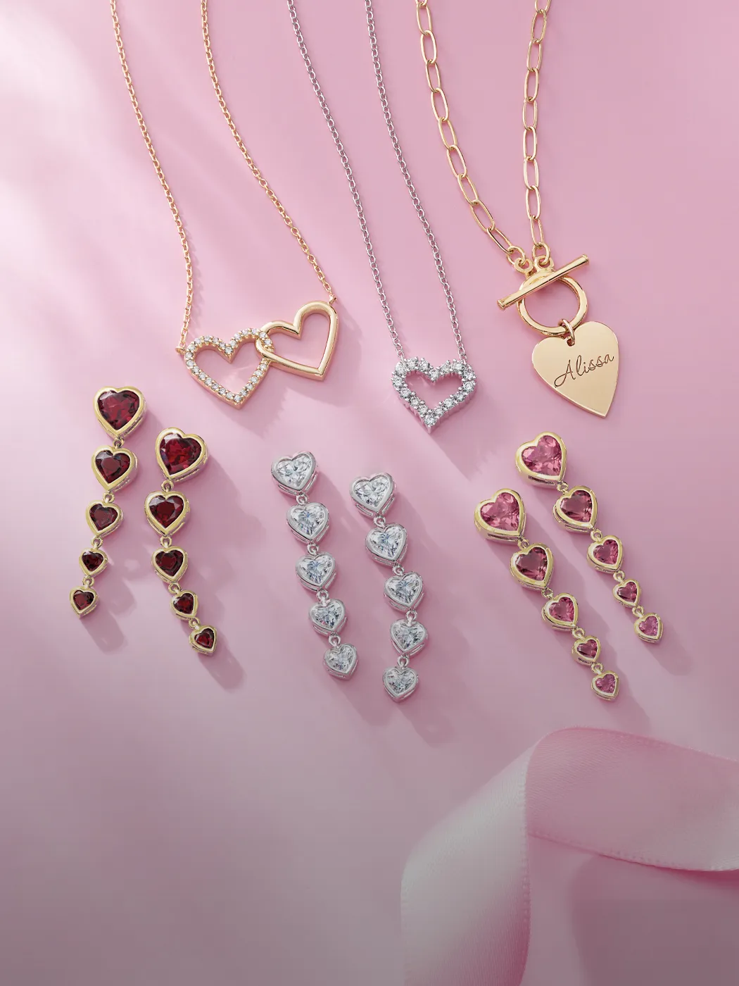 Heart-shaped gold and silver jewelry on pink background.