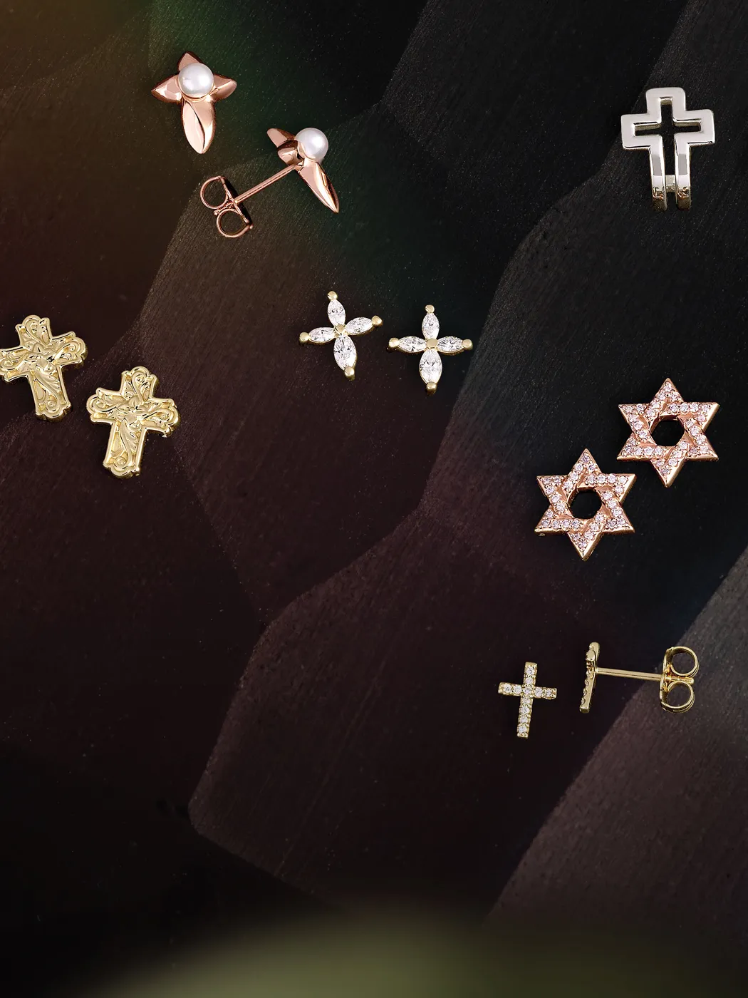 A variety of religious-themed earrings, including crosses and stars, displayed on a dark background.