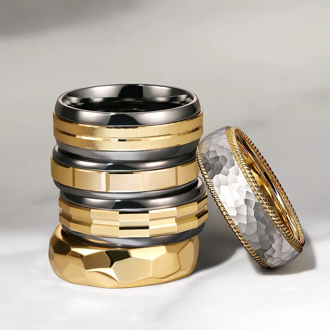 Stack of stylish rings in gold and silver tones, showcasing various textures and designs. Shop at J.A. Jewelers & Co.