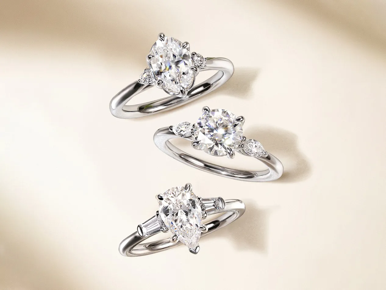 Three elegant diamond engagement rings displayed on a soft background. Visit J.A. Jewelers & Co. for more.