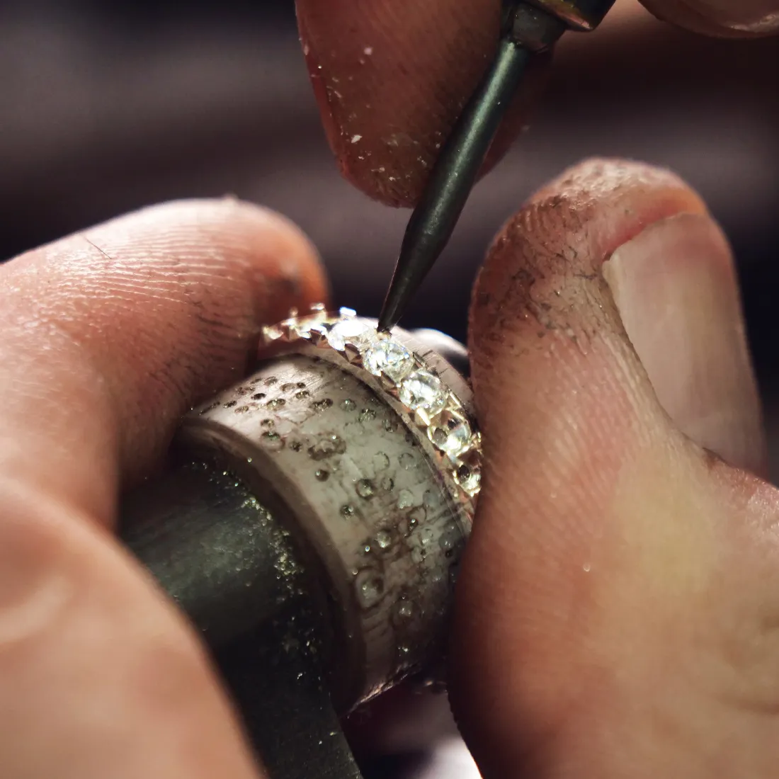 A jeweler meticulously setting diamonds into a ring, showcasing craftsmanship at J.A. Jewelers in Farmington.