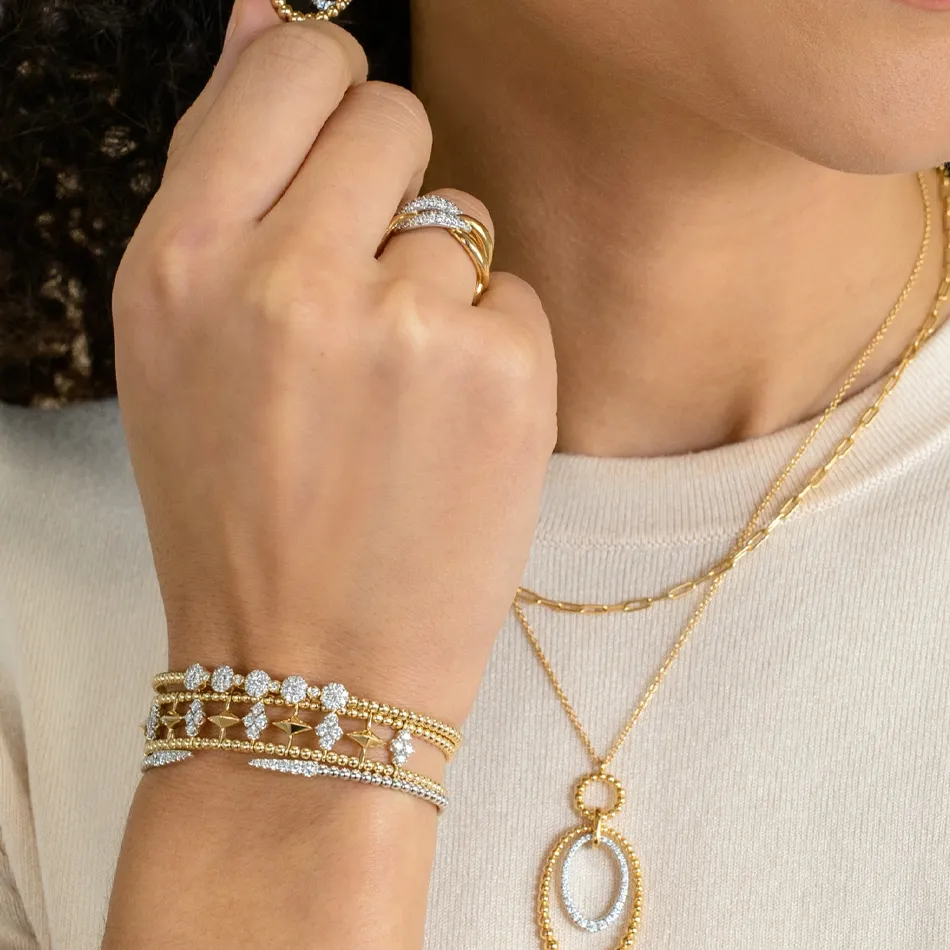Close-up of a hand adorned with gold and diamond jewelry, including rings, bracelets, and necklaces.
