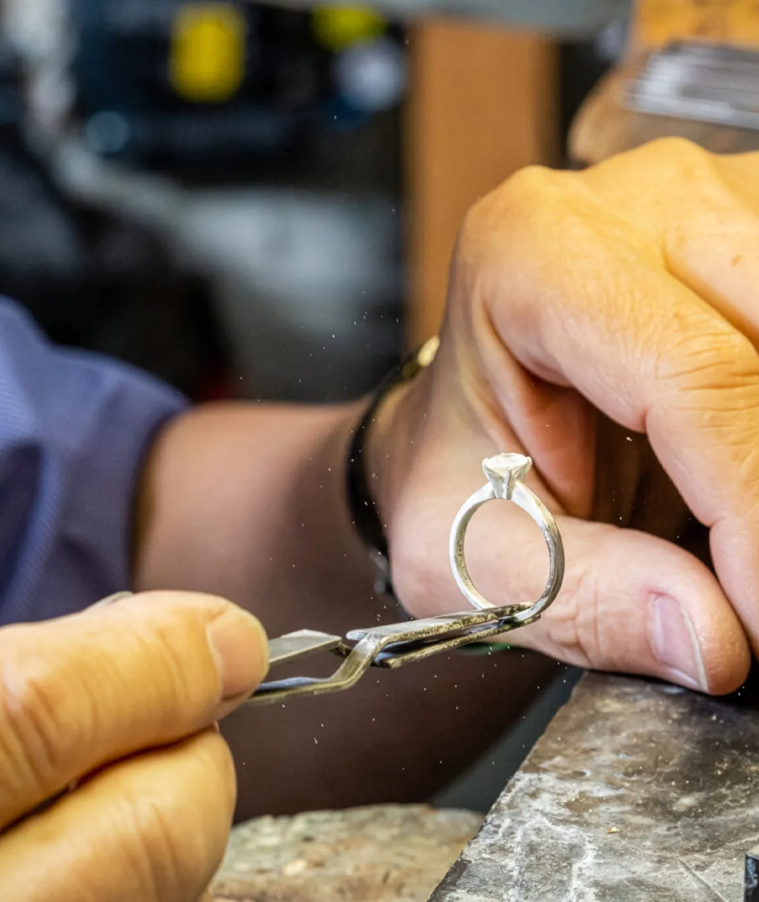Jeweler working on a silver ring with a diamond, showcasing craftsmanship at J.A. Jewelers in Farmington.