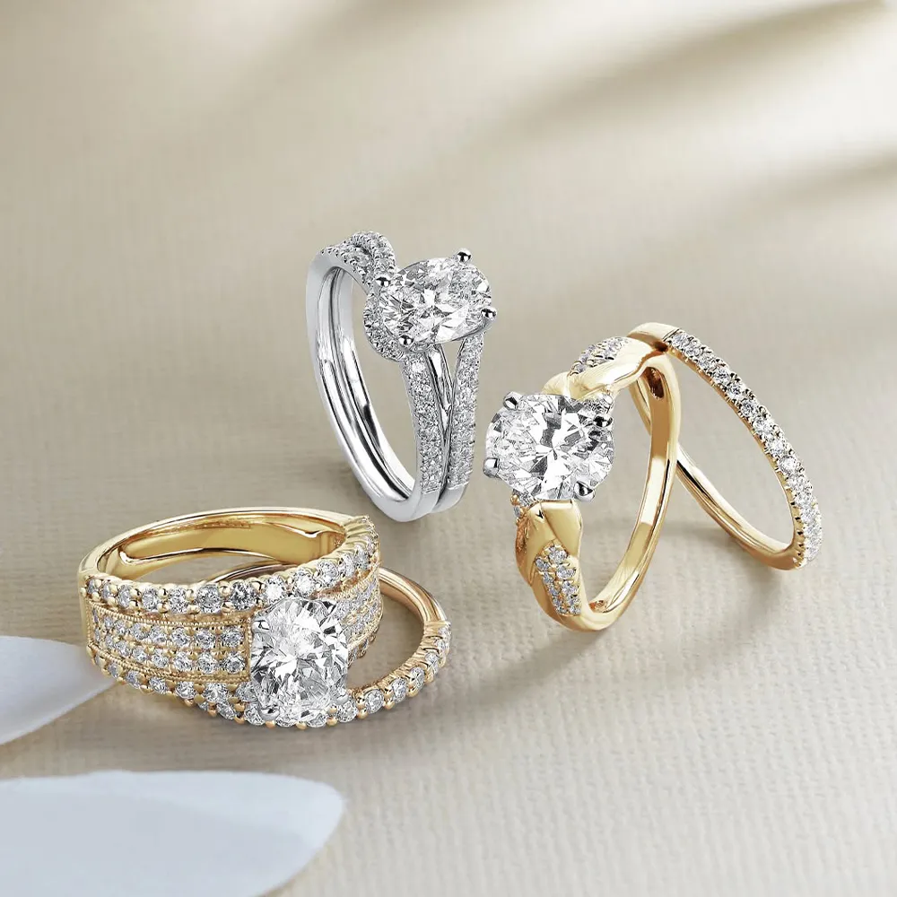 Three diamond engagement rings in gold and silver settings on a beige surface.