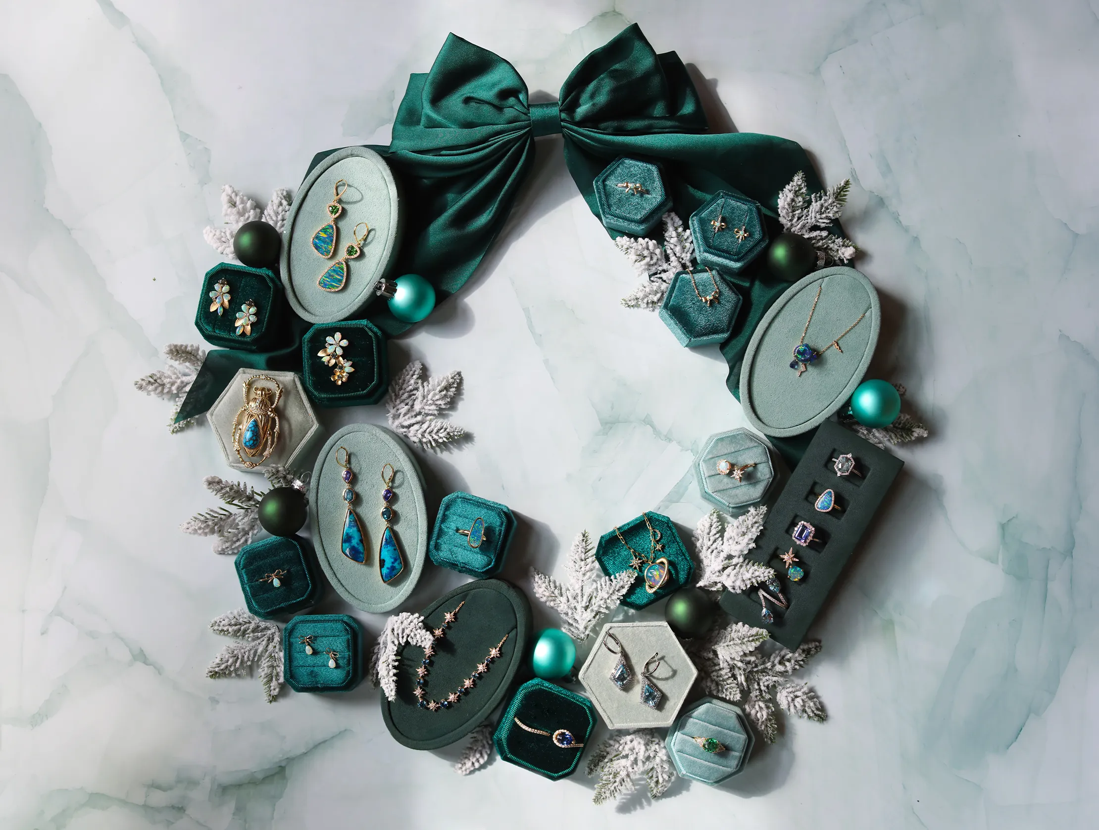 A wreath made of jewelry boxes with various earrings, rings, and necklaces, adorned with teal ribbon and ornaments.