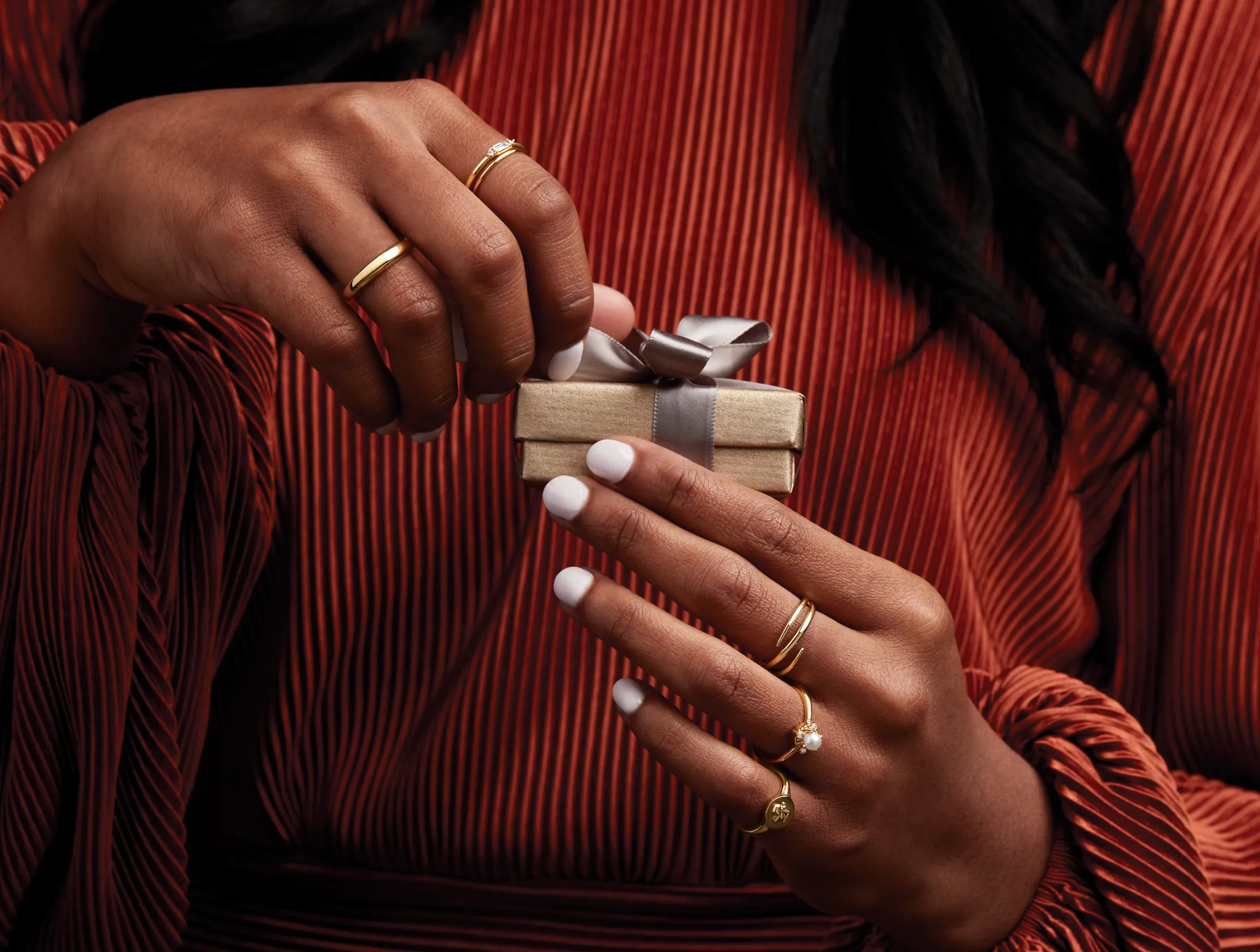 Close-up of a woman holding a gift box, showcasing gold rings. Shop at J. Anthony Jewelers in Neenah.