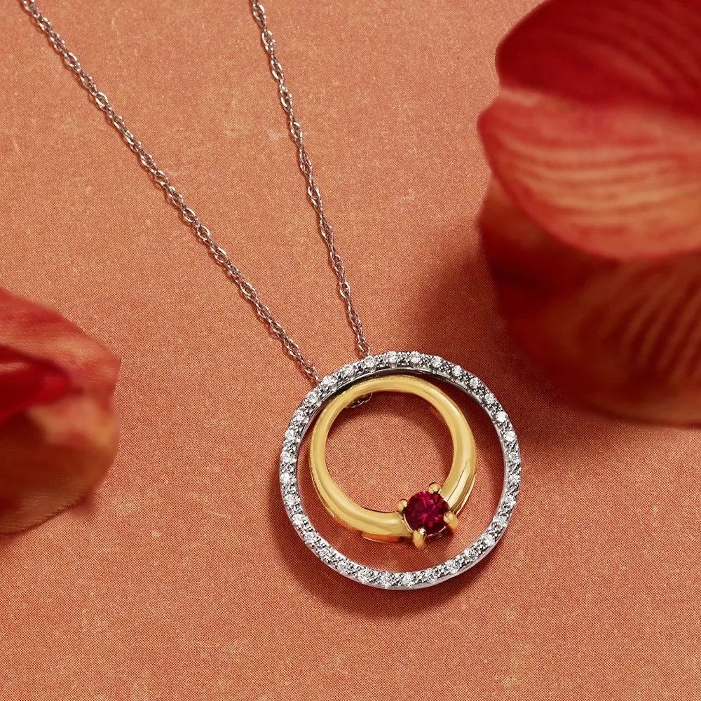 Gold and silver pendant necklace with a ruby stone, surrounded by sparkling diamonds, on a textured background.