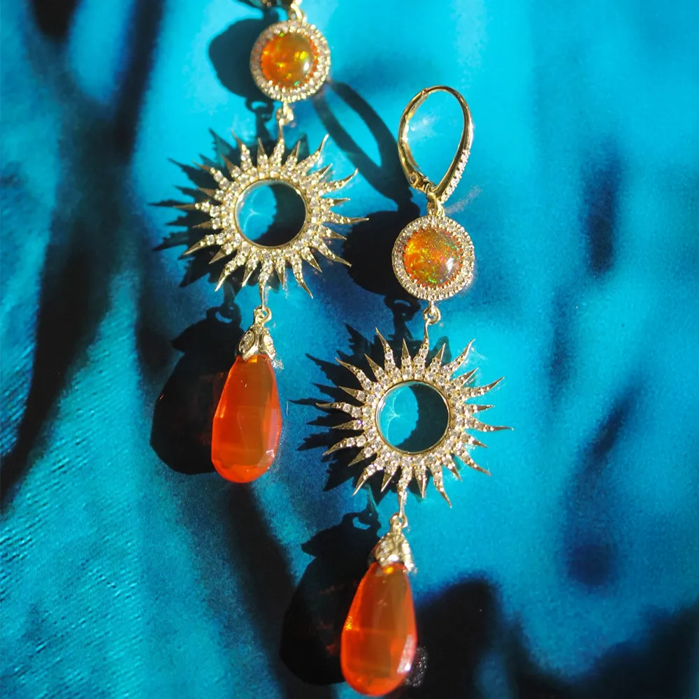 Gold sunburst earrings with orange gemstones, perfect for adding a vibrant touch to any outfit.