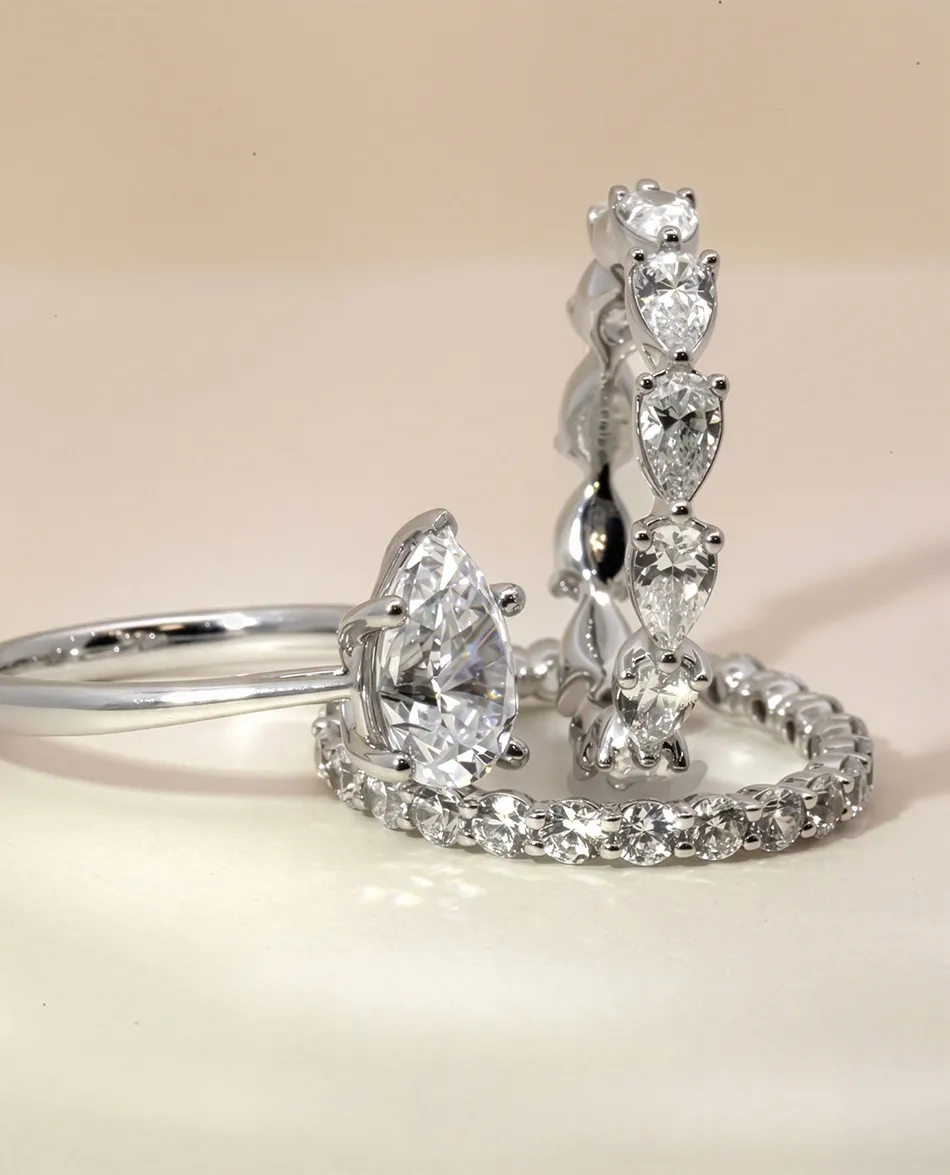 Diamond rings with pear-shaped stones and eternity band. Click to shop anniversary bands.