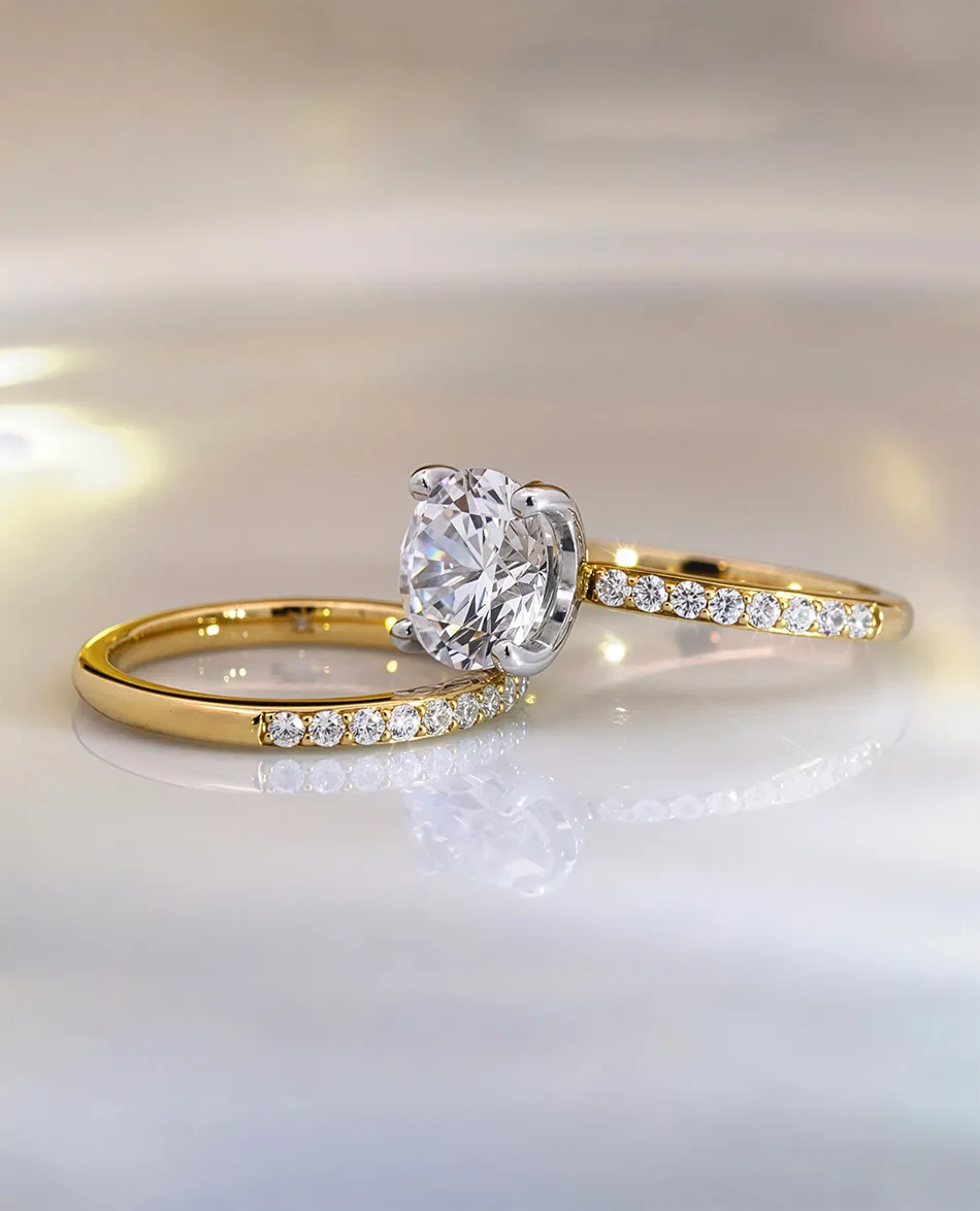 Gold engagement ring with a large diamond and matching band with smaller diamonds. Click to shop bridal sets.
