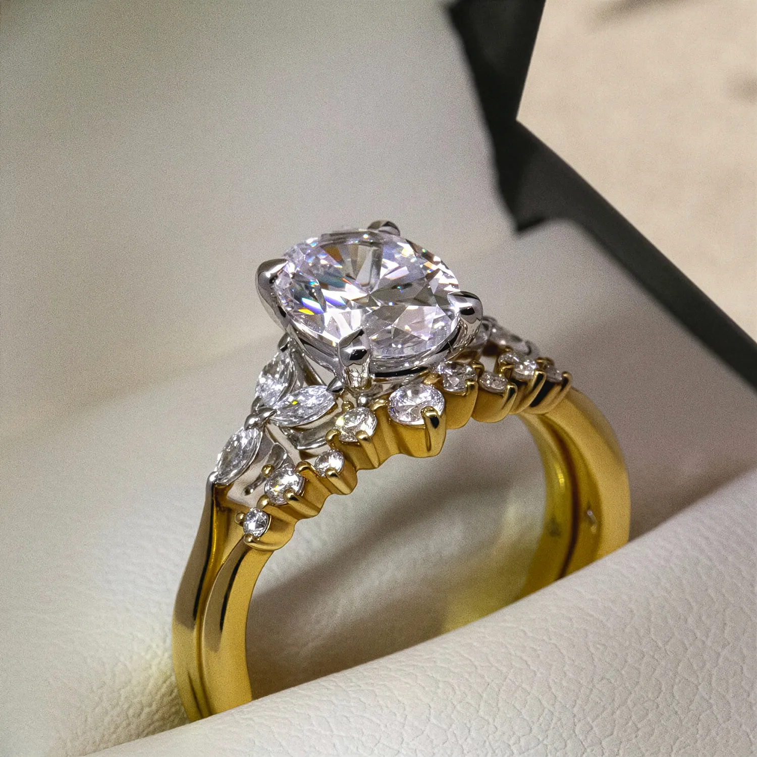 A gold engagement ring with a large diamond and smaller diamonds in a jewelry box.