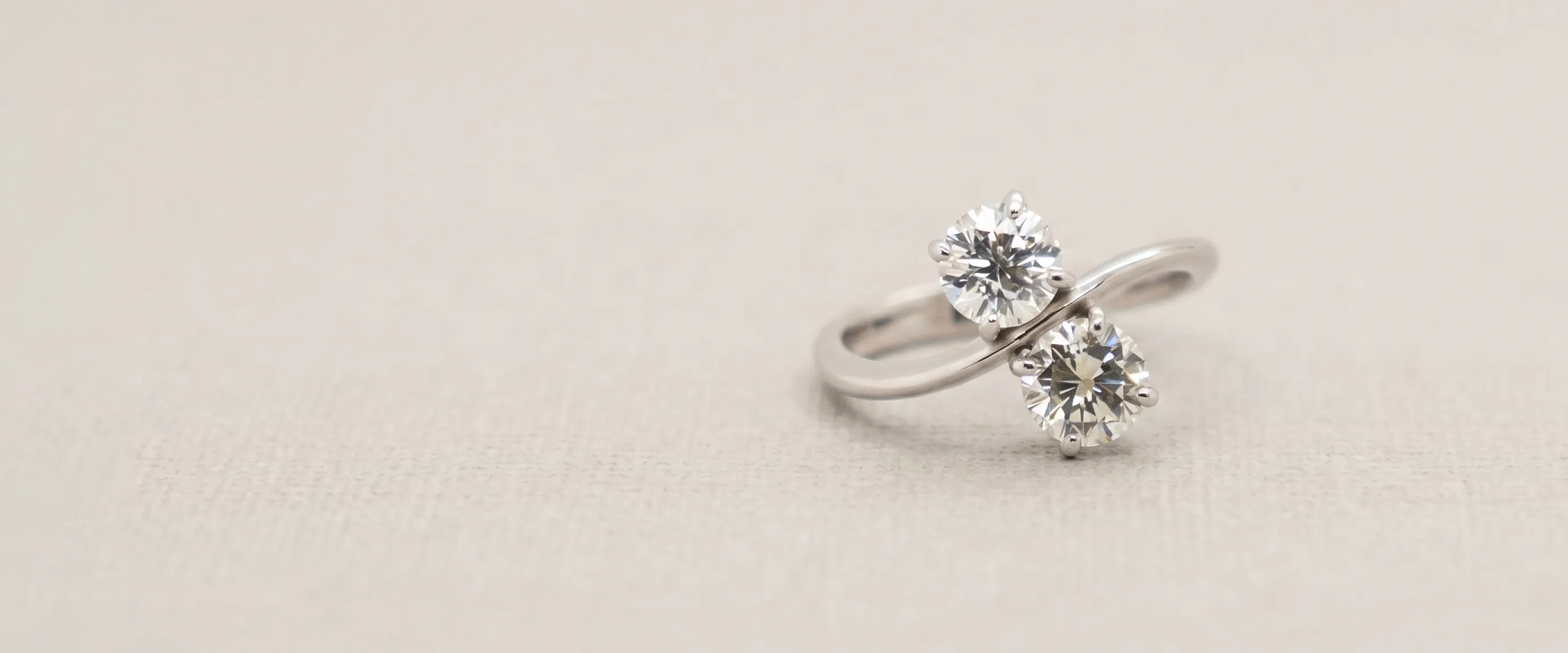 Two-stone diamond ring on a light background. Book an Appointment at Jayson Jewelers.