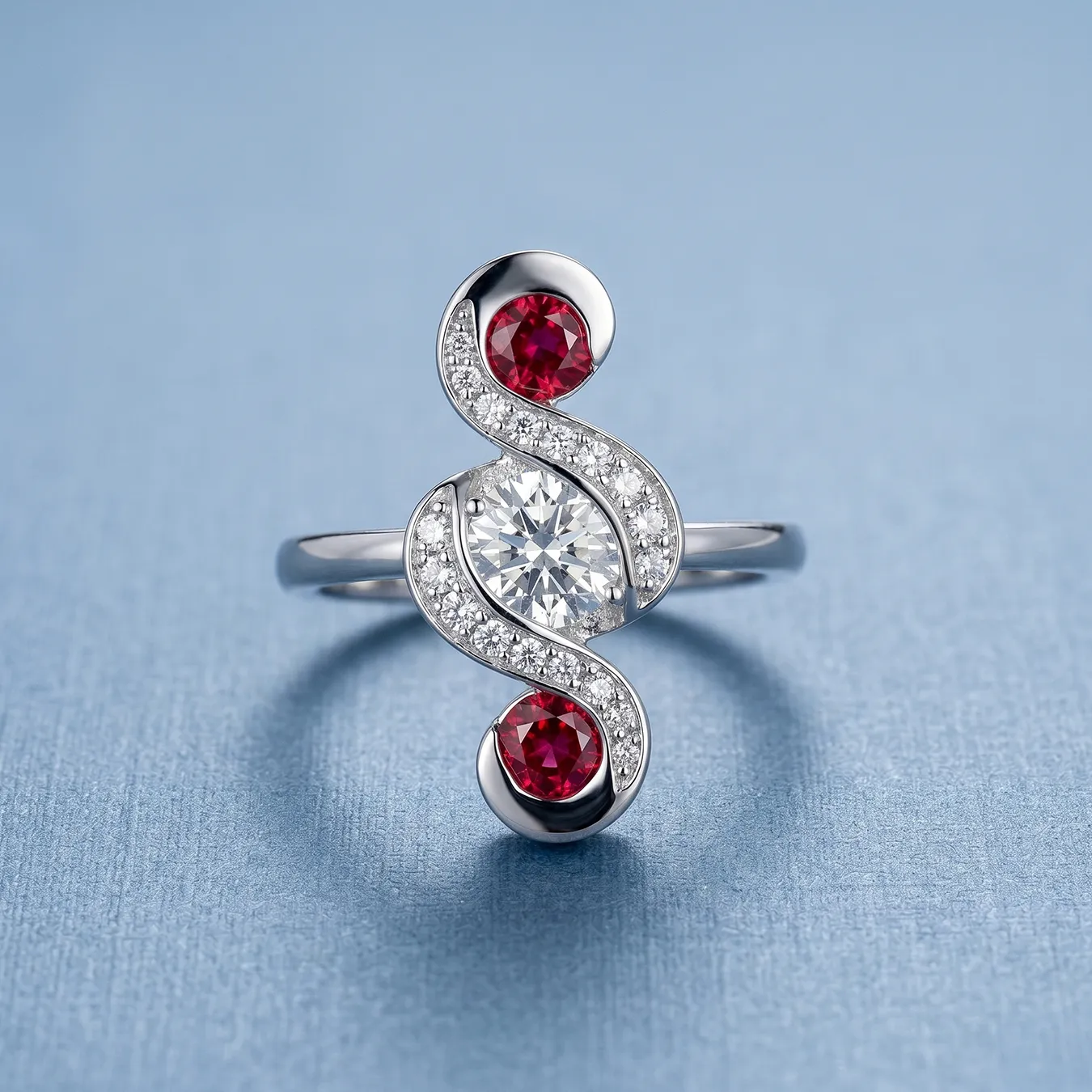 Elegant ring with a central diamond and two red gemstones on a blue background.