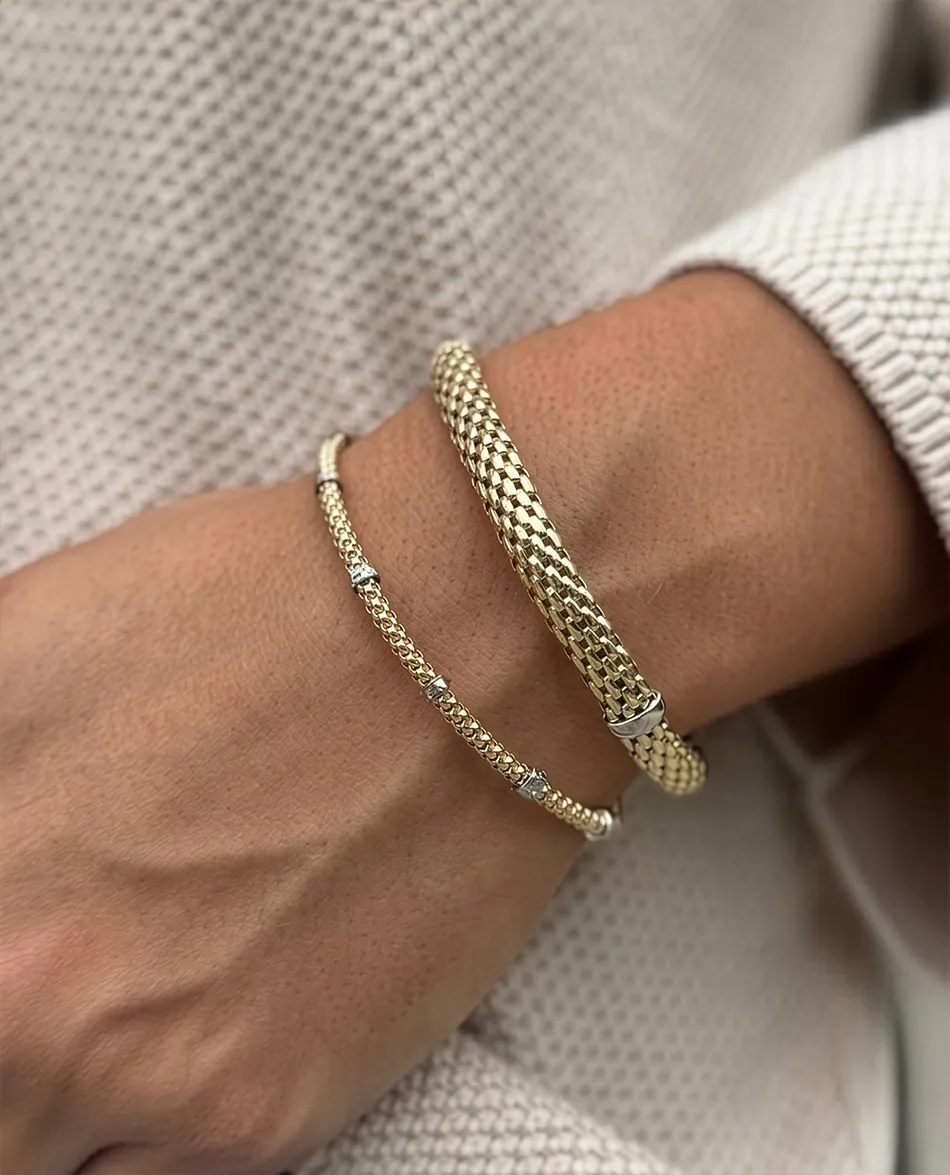 Gold bracelets on a wrist, textured sweater background.