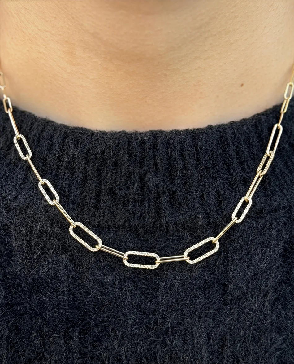 Gold chain necklace with rectangular links on a dark sweater. Click to shop chains.