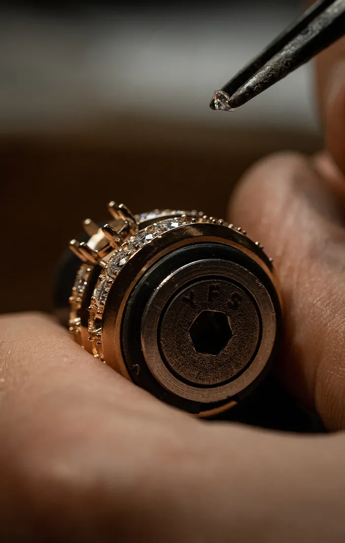 Close-up of a jeweler setting a diamond in a ring. Make an Appointment.