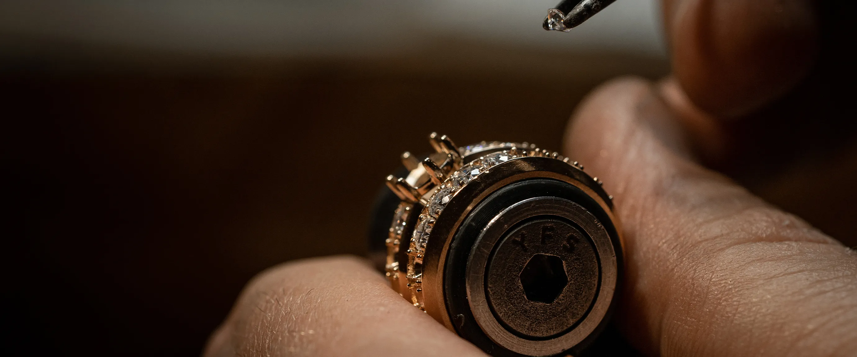 Close-up of a jeweler setting a diamond in a ring. Make an Appointment.
