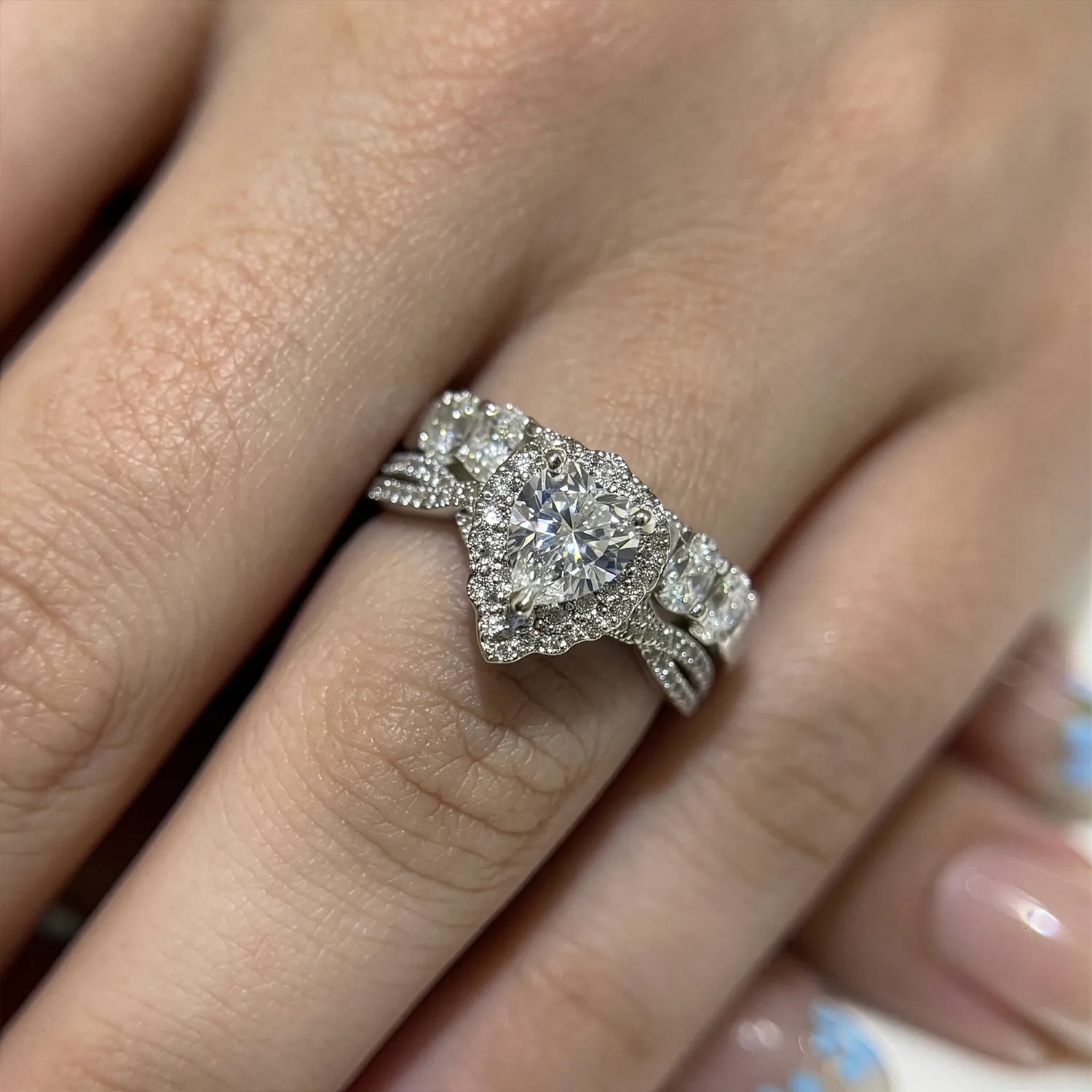 A hand wearing a diamond engagement ring with intricate detailing.
