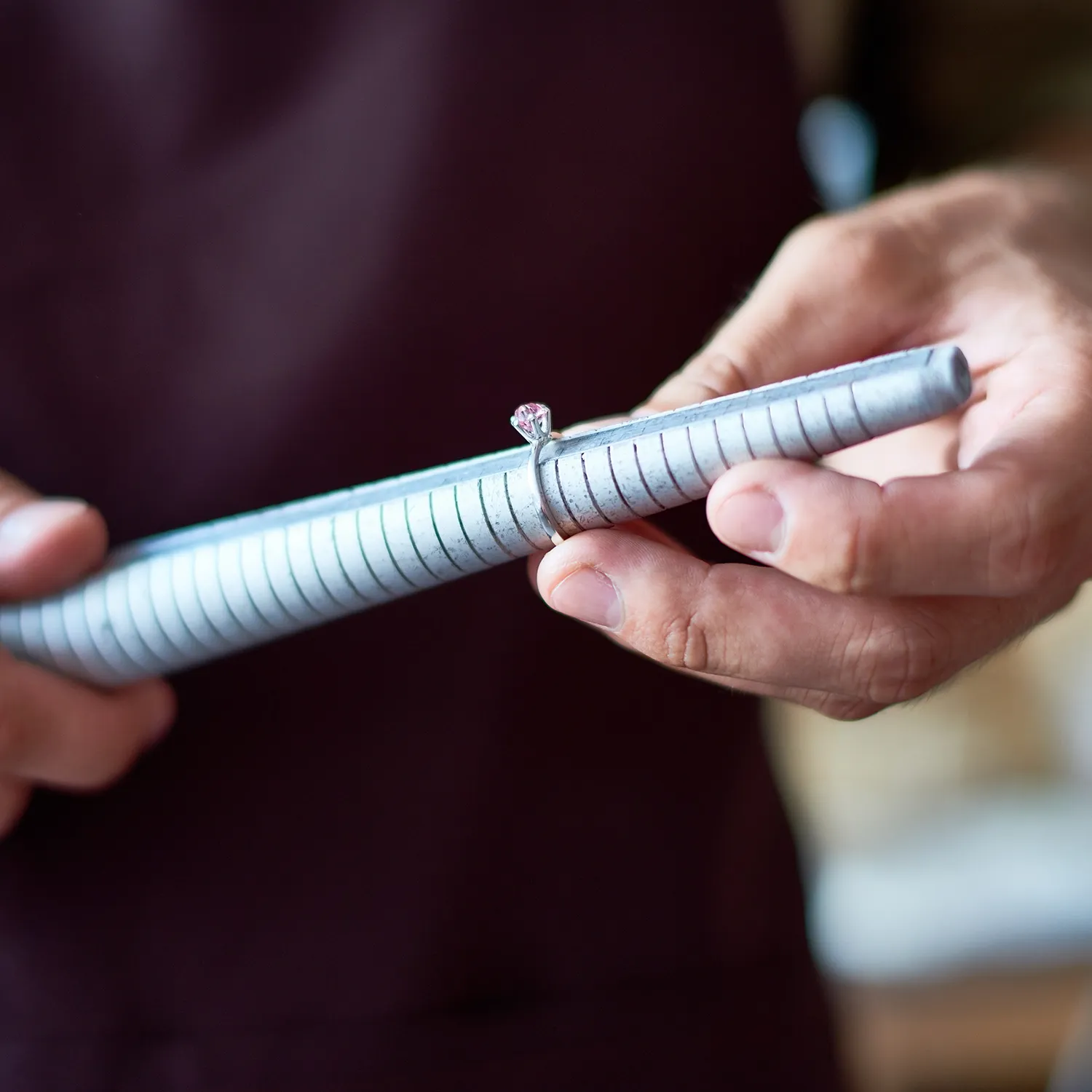 A person measures a ring size using a ring mandrel at Jayson Jewelers.