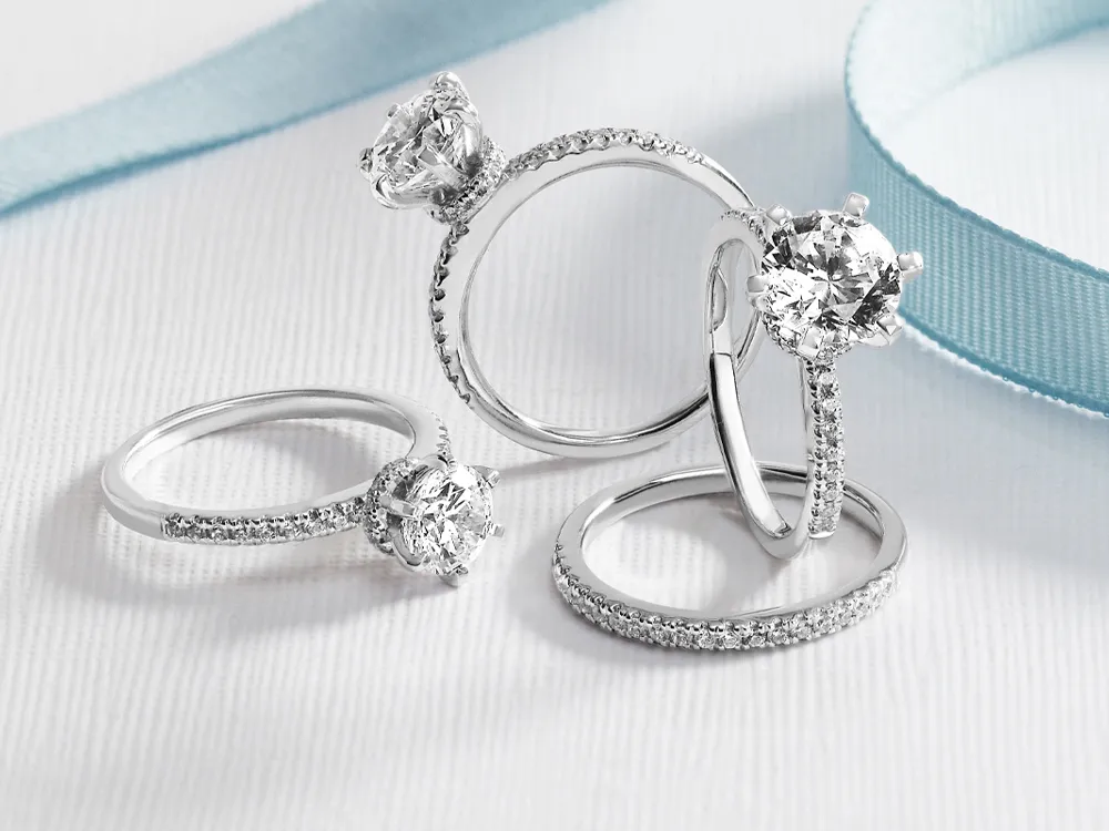 Four elegant diamond rings displayed on a soft background, showcasing fine jewelry.