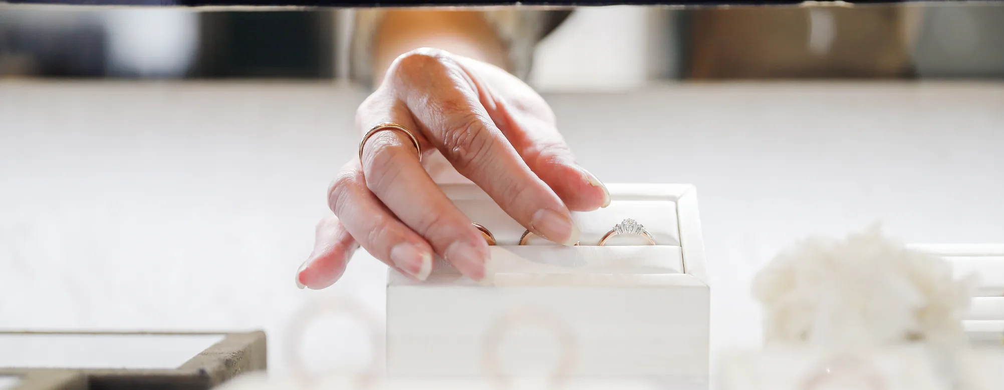 A hand reaching for a diamond engagement ring in a jewelry display at Genesis Jewelry in Muscle Shoals.