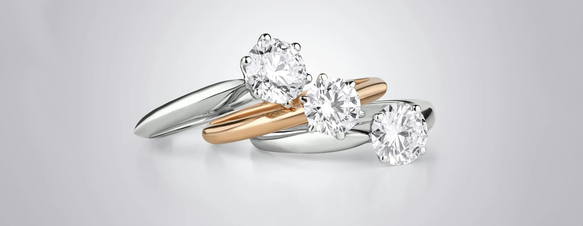 Three elegant diamond engagement rings in white and rose gold settings.