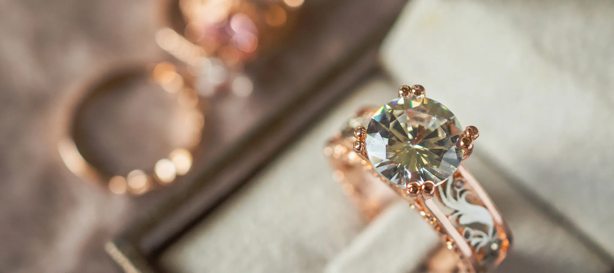 Elegant rose gold engagement ring with a large diamond, displayed on a soft fabric background. Visit Genesis Jewelry.