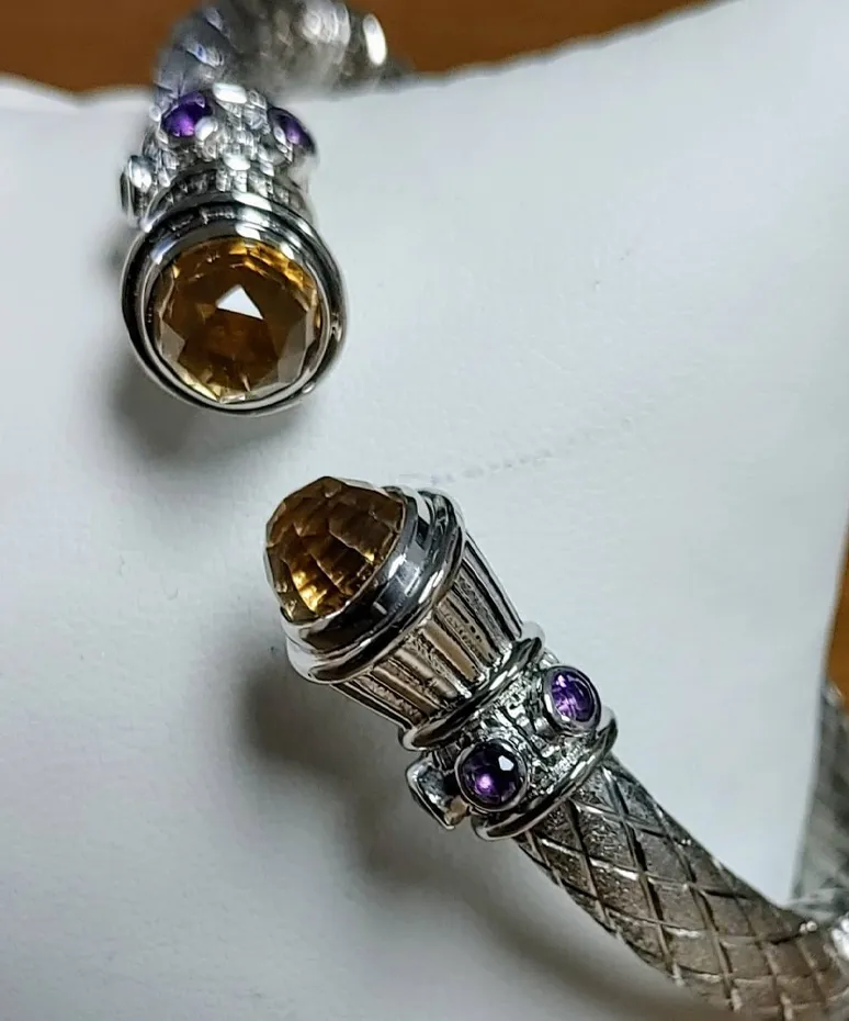 Elegant silver bracelet featuring a large citrine and amethyst accents, displayed on a white cushion.