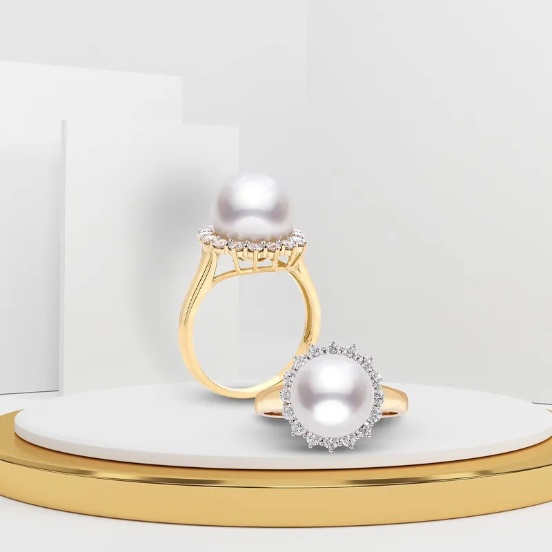 Elegant pearl rings with diamond accents displayed on a circular stand.