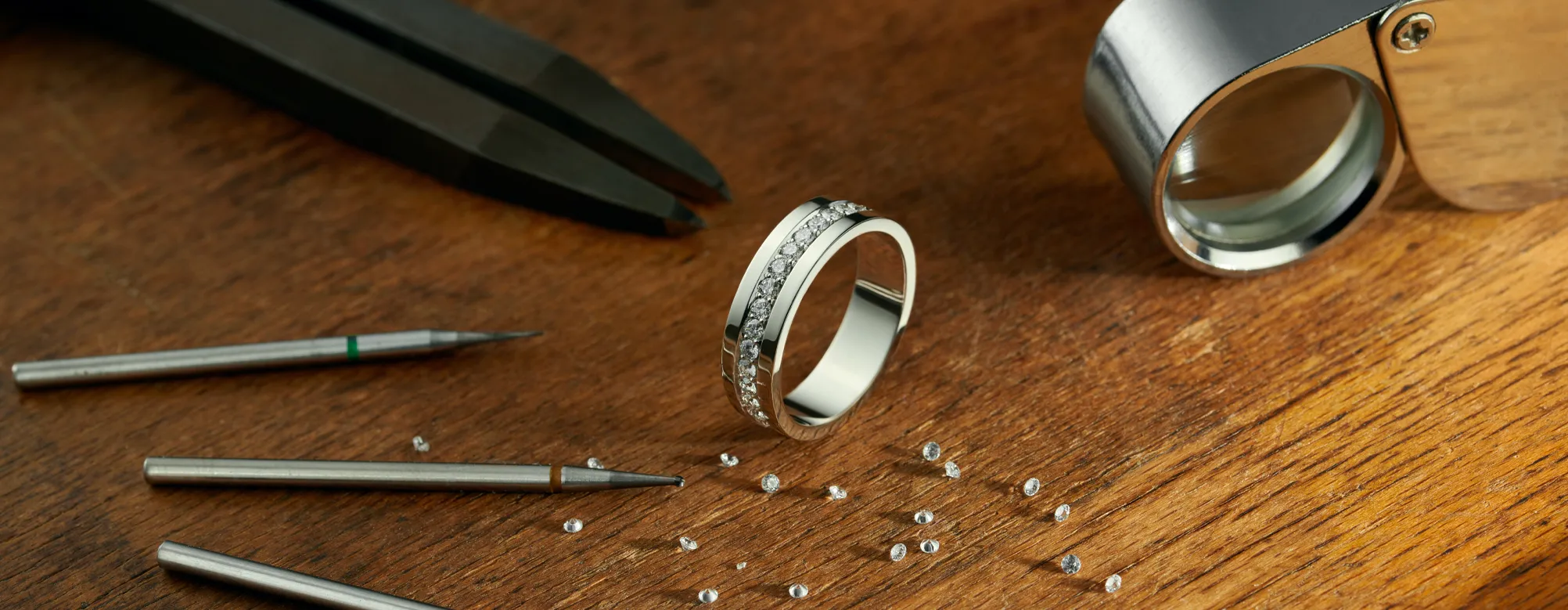 Jewelry tools and a diamond ring on a wooden surface, showcasing in-house jewelry services at Genesis Jewelry.