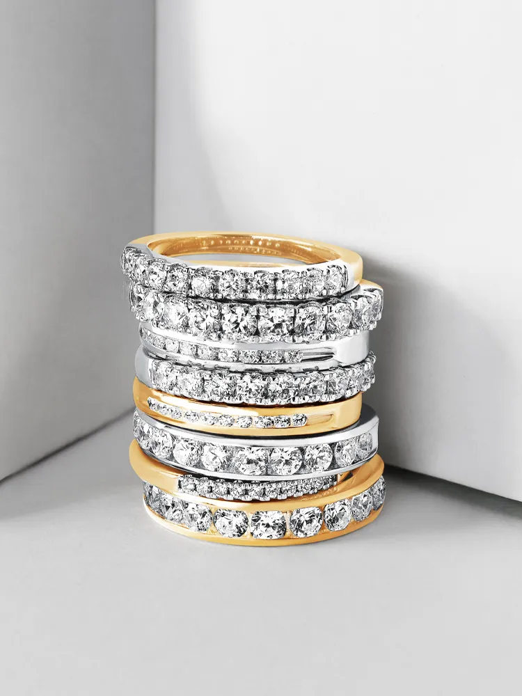 Stack of elegant gold and silver rings with sparkling diamonds, showcasing fine jewelry.