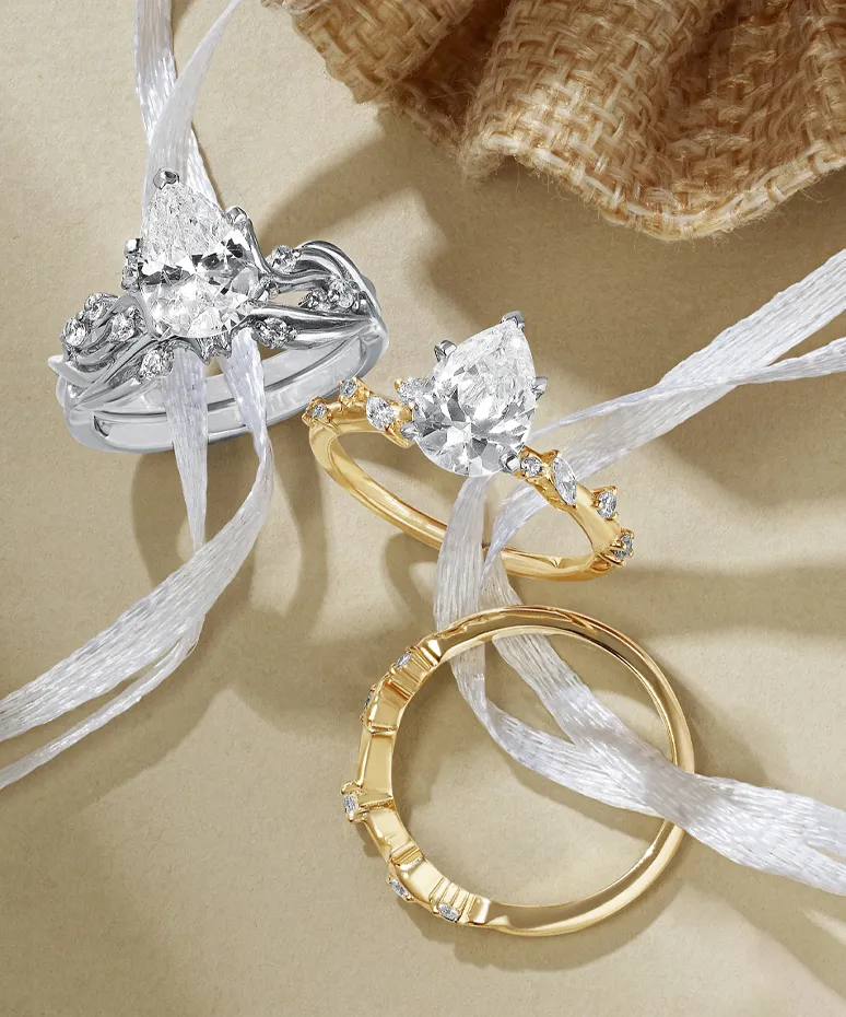 Three elegant rings featuring diamonds, displayed with white ribbons on a neutral background.