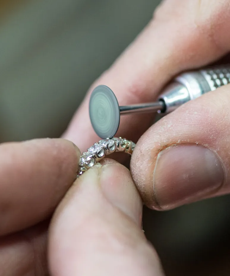 Jeweler polishing a diamond ring with a rotary tool at Genesis Jewelry in Muscle Shoals.