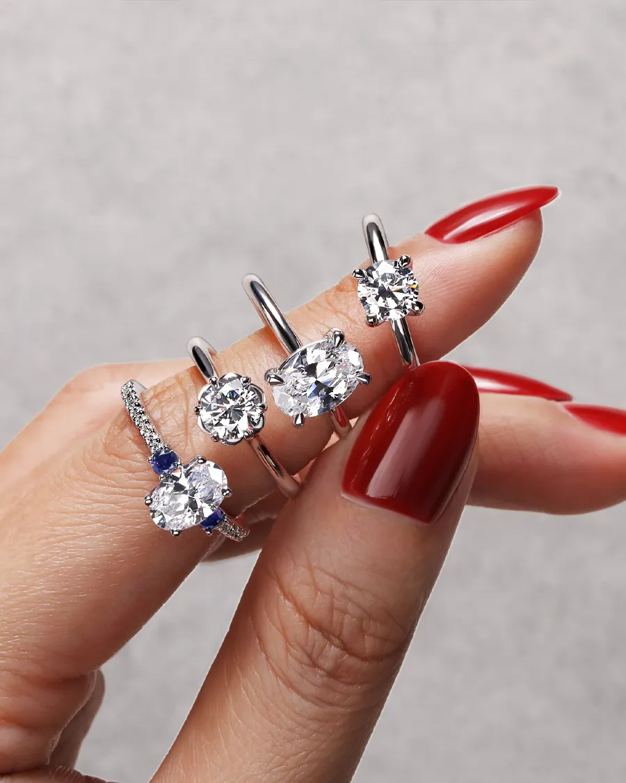 Three elegant rings with sparkling stones displayed on a finger with red nails. Explore more at Jim Kryshak Jewelers.