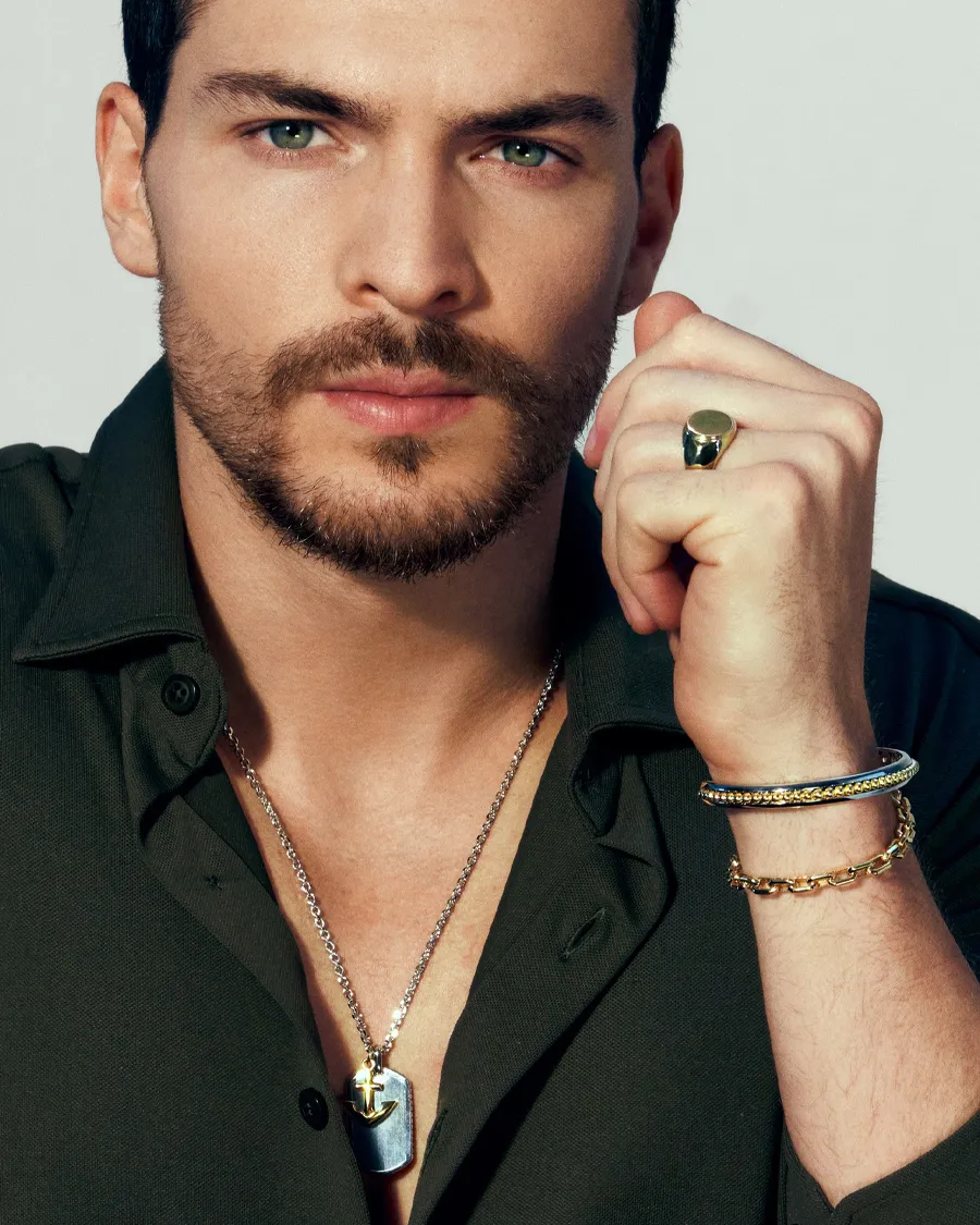 Close-up of a man with a beard wearing jewelry, including a necklace and rings, showcasing style and elegance.