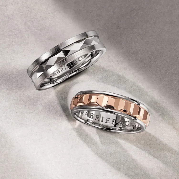 Two elegant wedding bands: one silver with a faceted design, the other rose gold with a hexagonal pattern.