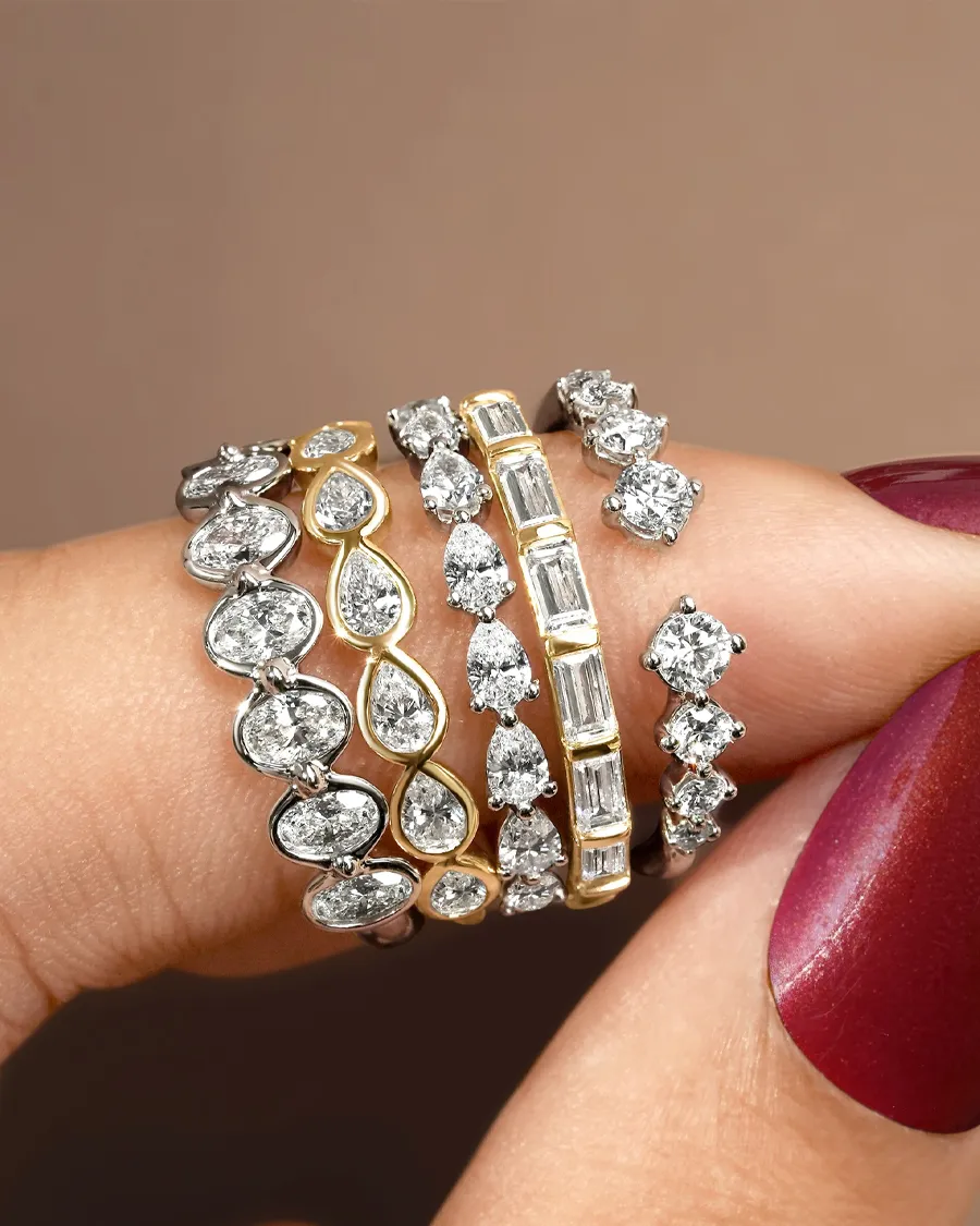 A hand displaying multiple elegant diamond rings in various styles and settings. Shop at Jim Kryshak Jewelers in Wausau.
