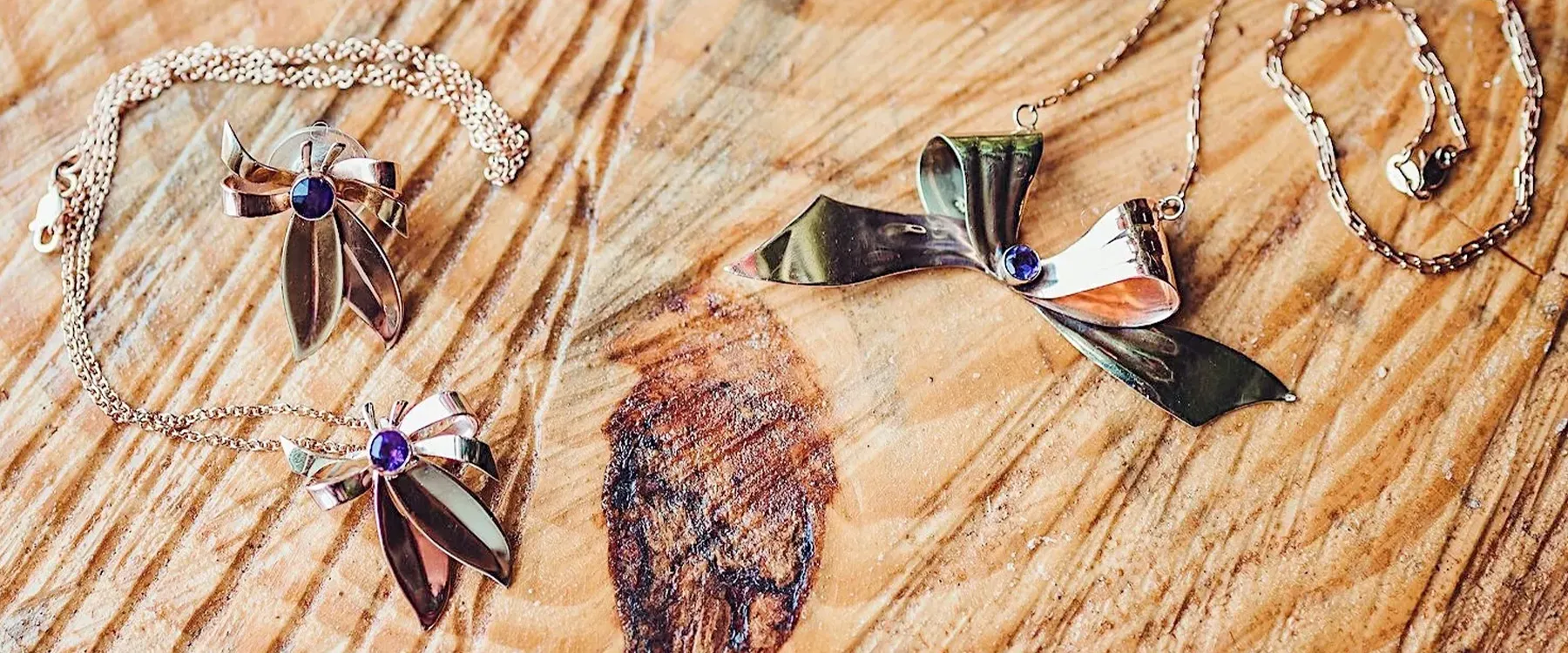 Vintage jewelry pieces featuring floral designs with purple stones on a wooden surface. Explore more at Joint Venture Jewelry