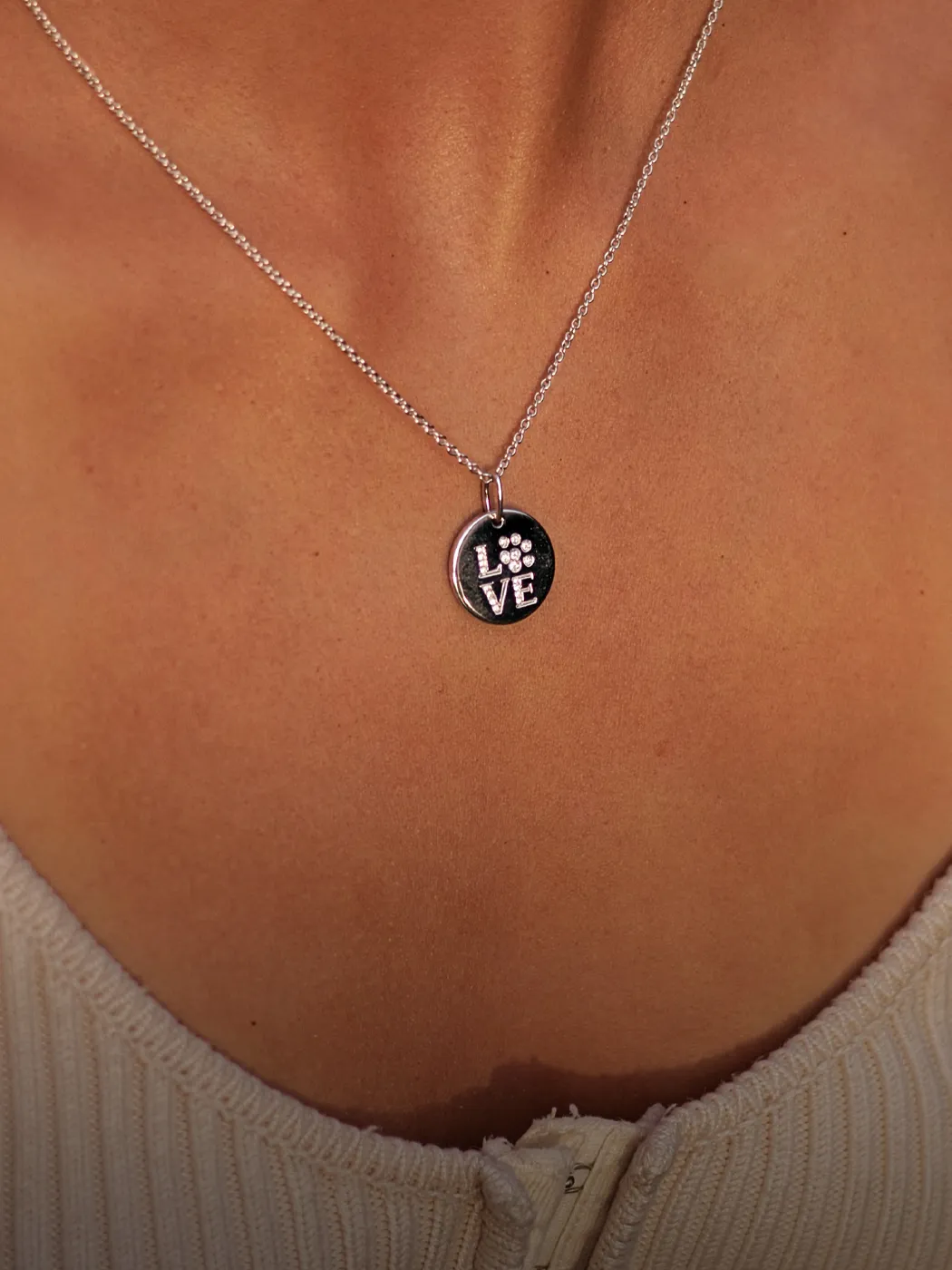 Silver necklace with a round pendant featuring the word 