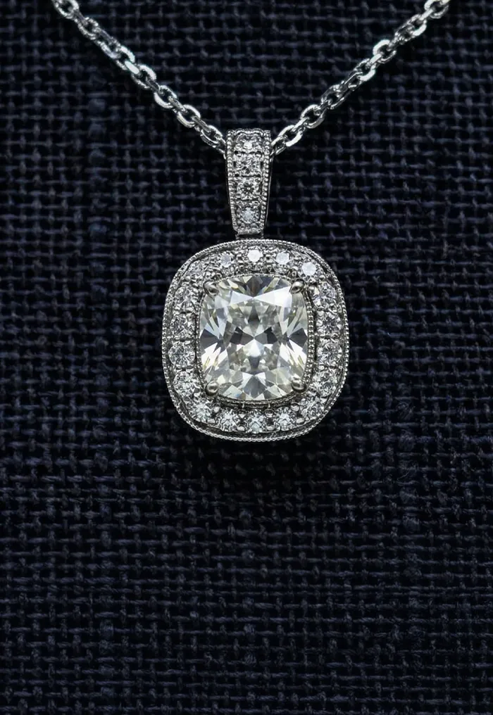 Diamond pendant necklace with halo setting on a dark textured background.