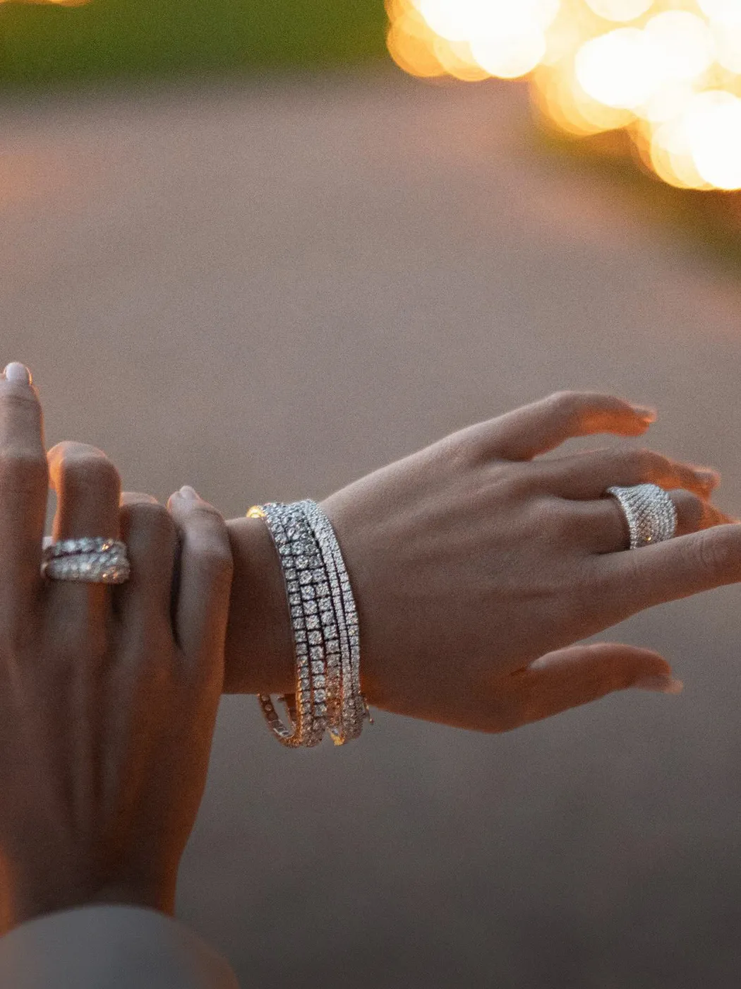 Hands adorned with diamond tennis bracelets and rings, showcasing fine jewelry.