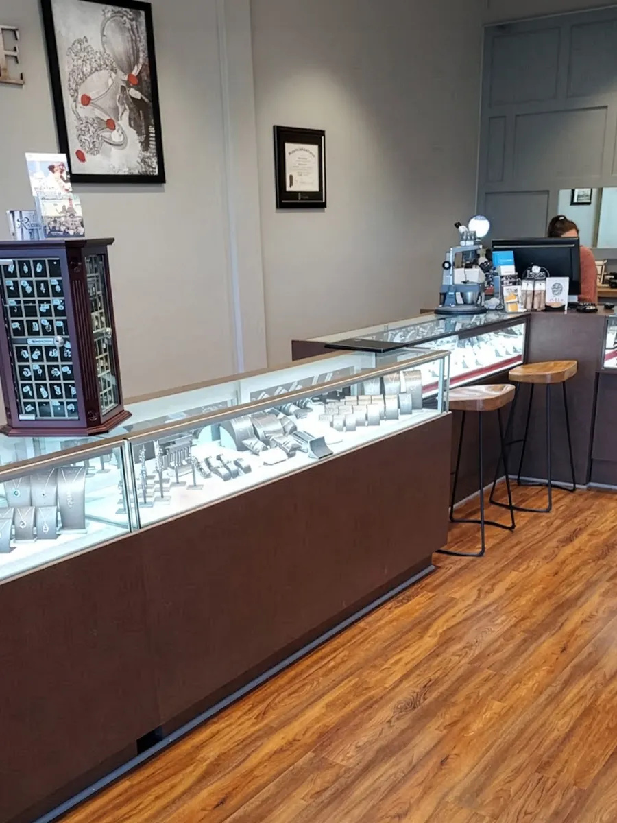 Jewelry store interior with display cases, stools, and framed art on the wall.