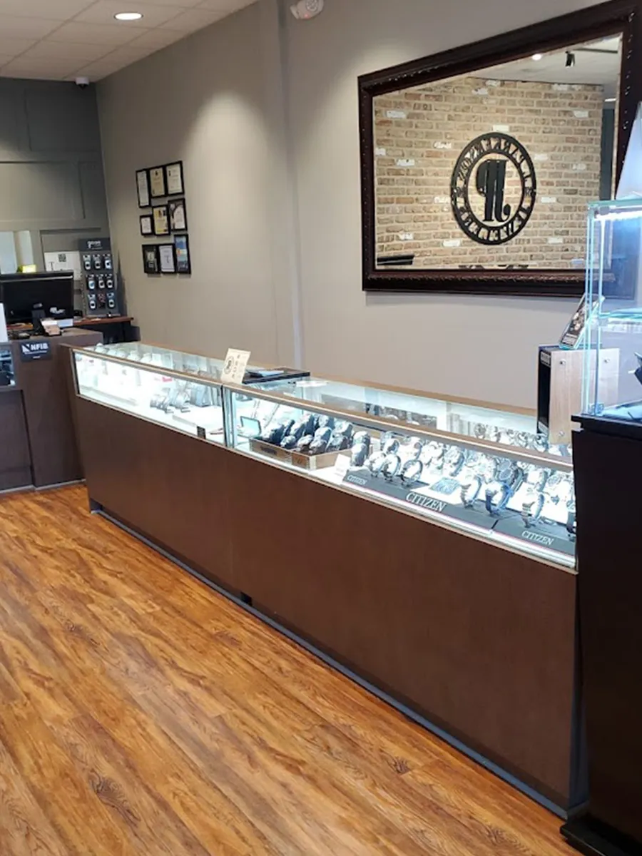 Jewelry store interior with display cases of watches and a large mirror on the wall.