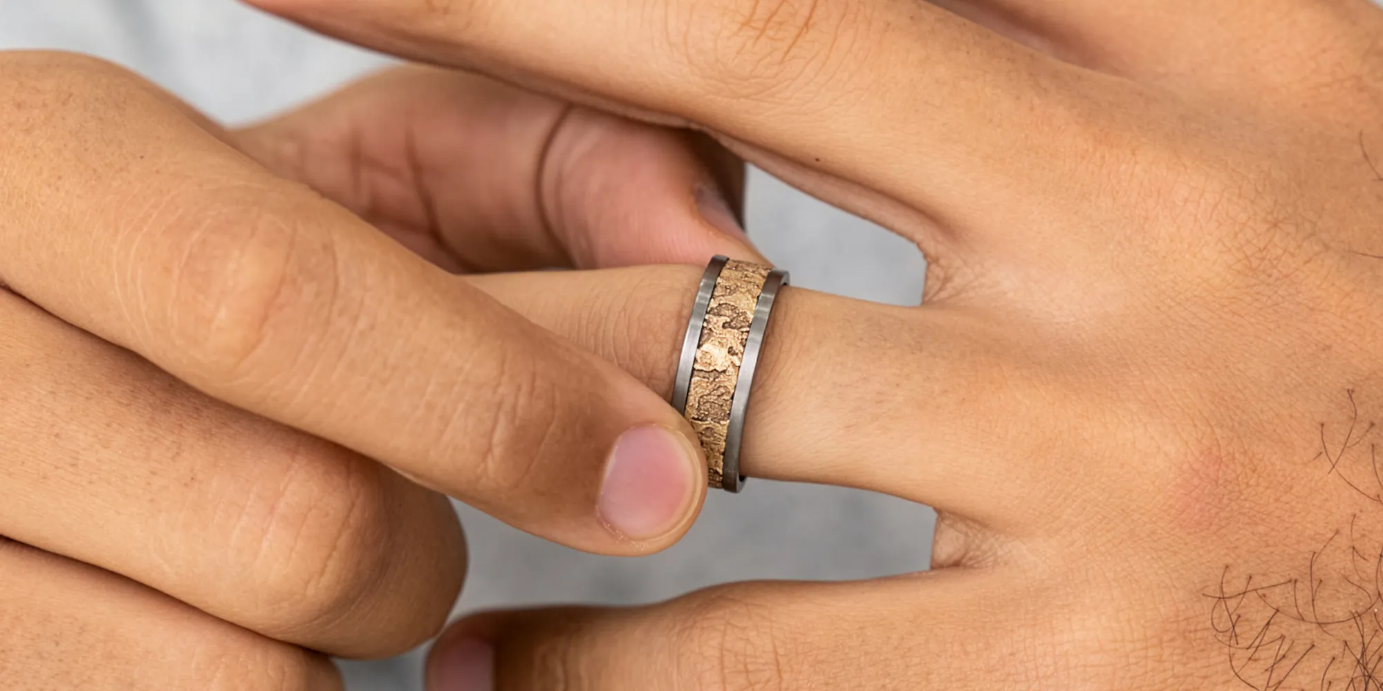 Close-up of a hand adjusting a textured metal ring on a finger.