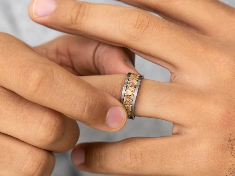 Close-up of a hand adjusting a textured metal ring on a finger.