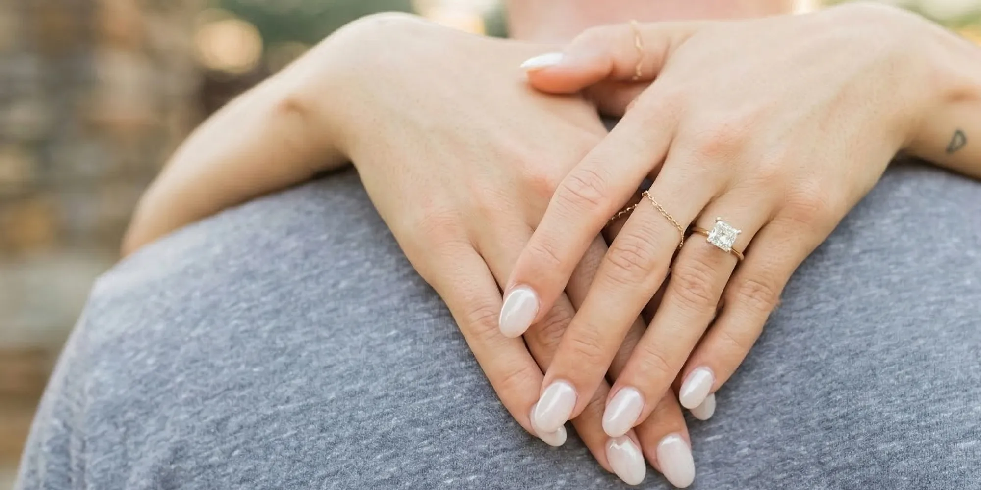 Hands with manicured nails and engagement ring on a person's back.
