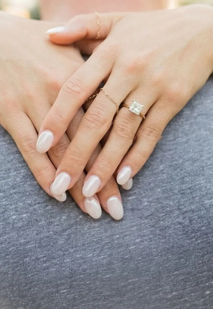 Hands with manicured nails and engagement ring on a person's back.